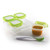 Four OXO Tot clear plastic storage containers with bright green lids arranged with one open container filled with orange purée and a white and green feeding spoon.