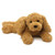 Gund Muttsy golden brown plush puppy dog toy in lying down pose on white background, soft curly fur texture
