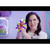 Woman smiling while squeezing an orange Doctor Squish squishy with colorful graphic burst effect