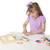 Melissa & Doug Friendship Stamp Set - young girl in purple top using wooden stamps on paper with inkpad, pencils and wooden storage box on white table | Peekaboobaby