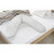 Light grey Theraline muslin pillow cover positioned on bed with white sheets and neutral bedding