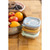 Three stacked Beaba meal box containers beside wooden bowl of fresh fruit