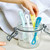 Child's hand holding Beaba silicone spoons in glass jar with towel backdrop