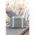 Beaba Paris pearl grey changing bag on surface, outdoor stone wall setting