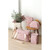 Multiple dusty pink pouches and coordinating storage bags displayed on wooden chair with potted plant and bread loaf.