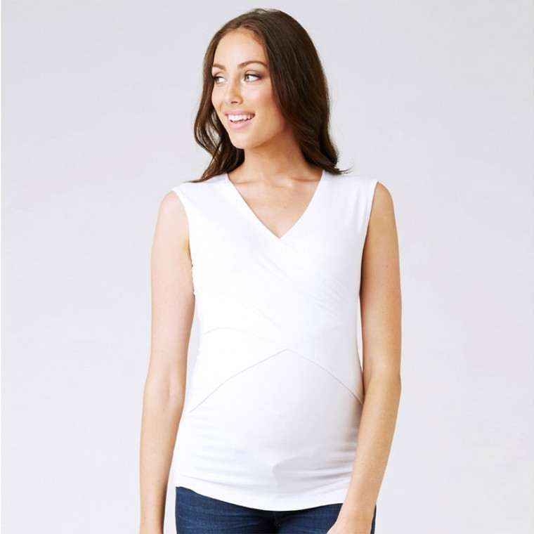 Woman wearing white Ripe Maternity sleeveless v-neck nursing tank top with fitted silhouette against grey background