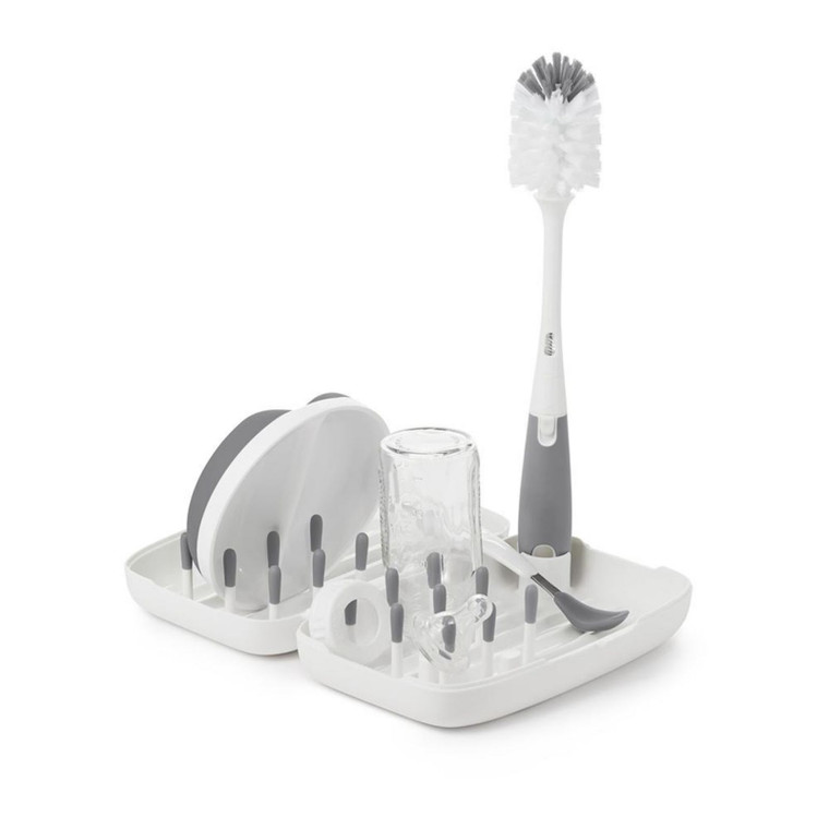 OXO Tot grey and white drying rack with bottle brush, holding baby bottles and accessories on white background