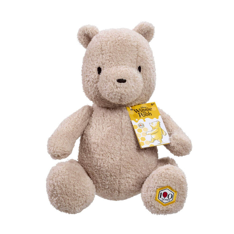 Winnie The Pooh 100th Anniversary Commemorative Soft Toy 19cm - cream plush Pooh bear with gold anniversary tag sitting upright 19cm | Peekaboobaby