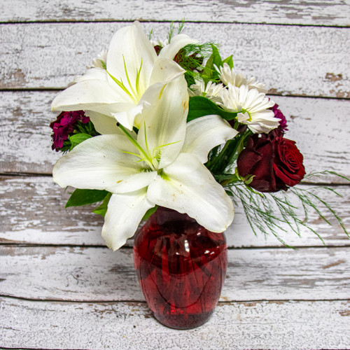 Red roses, white lilies, and white daisies in a red vase