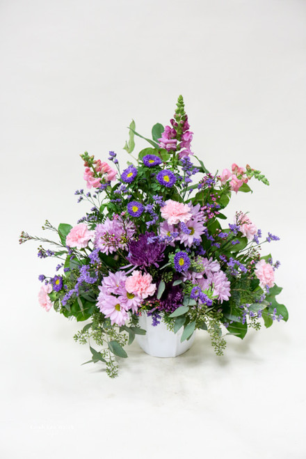 A simple wicker basket filled with soft lavender flowers and greenery. 
Small, simple, and thoughtful.