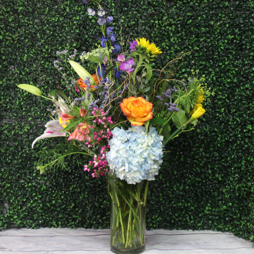 A Gorgeous unique fresh flower arrangement. Perfect for making a statement with locally grown sunflowers and lilies, mixed with premium roses.