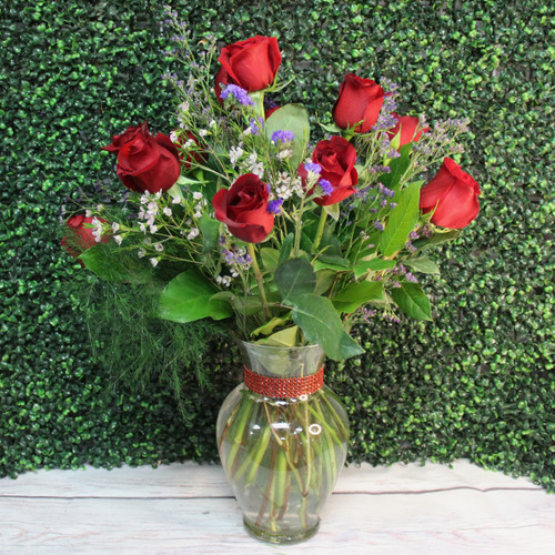 One dozen long stem roses with greens and filler in a tall glass vase
