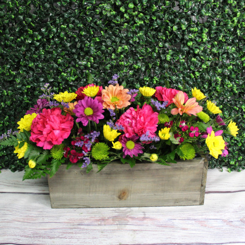 Summer flowers arranged low in a long rustic wooden box