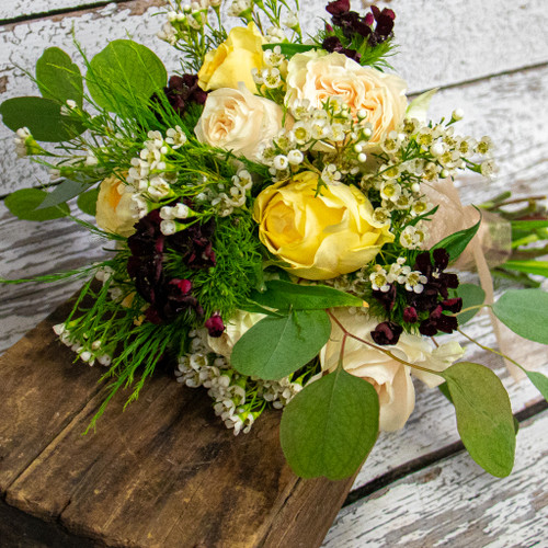 White and pale yellow roses accented with white waxflower and red dianthus in a nosegay style bridal bouquet. 

