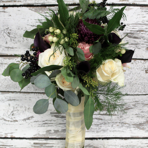 A mosegay style bridal bouquet with eucalyptus, blush and white garden roses, deep purple calla lilies accented with white and blue berries.