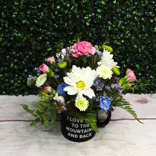 Another view of the “I love you to the mountains and back” mug with daisies and carnations