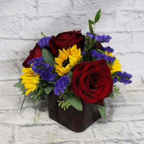 Red roses and sunflowers in a red cube vase