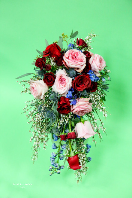 For a romantic spring look of red and pink roses, touch of blue delphinium and thistle and
don't forget the fragrant genesta. Subject to availability.