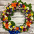 A rainbow of bright colors made of roses, mums, lilies, and carnations, finished with a blue satin bow