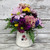 Bright daisies and carnations in a white mug that says Kindness Matters