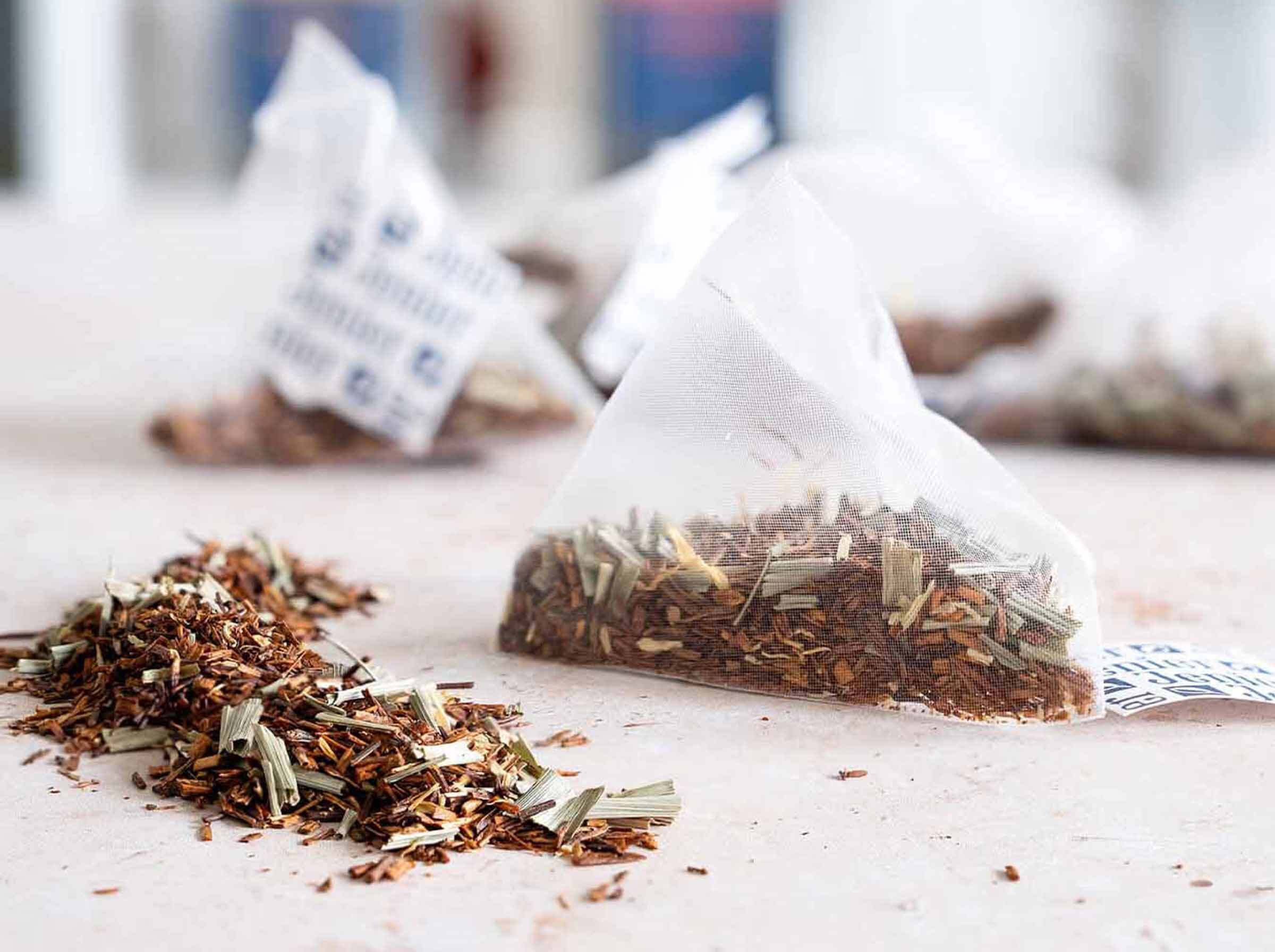 Close-up of a Jenier biodegradable pyramid tea bag alongside premium bulk loose leaf tea, demonstrating the consistent commercial quality used in our teabags.