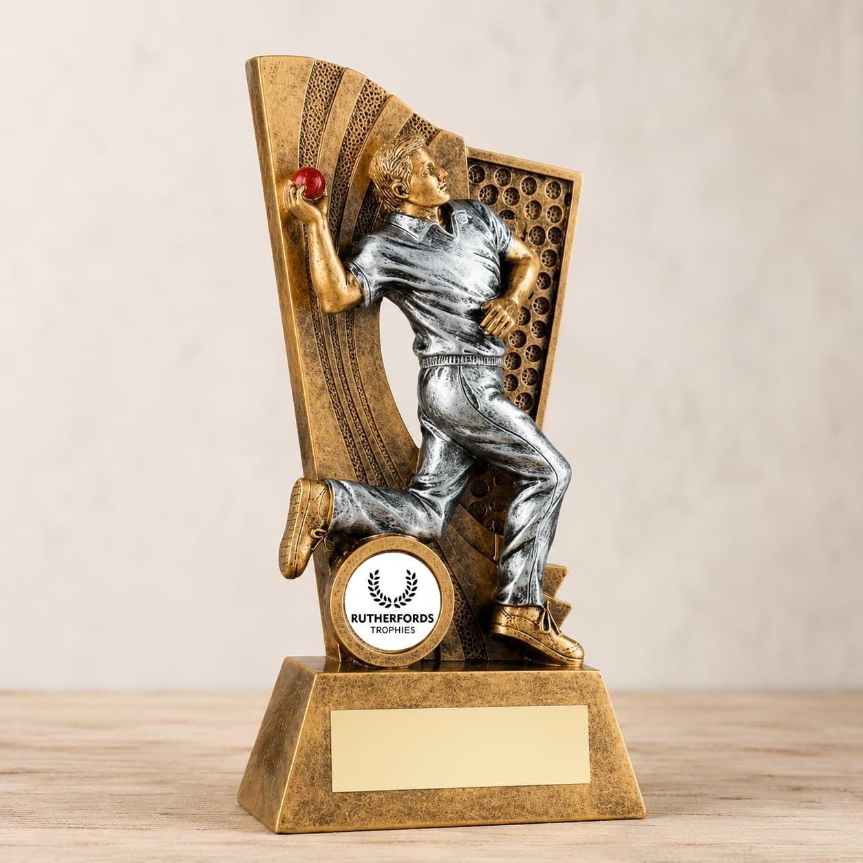 Antique gold and silver cricket bowler trophy holding a red ball with a personalised engraving plate