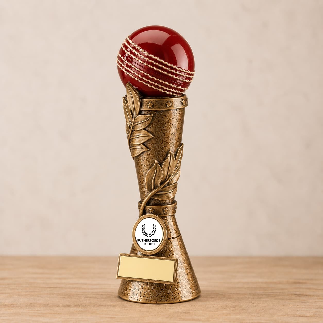 Antique gold cricket trophy pillar topped with a red cricket ball and personalised engraving plate