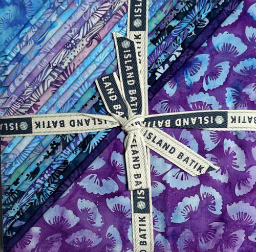 Lumin Fabrics Island Batik Secret Garden Batiks 10 Inch Squares, a set of colorful batik fabric squares with purple and blue floral and leaf patterns, tied with a black and white Island Batik ribbon.