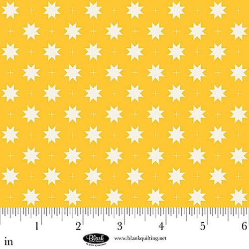 Blank Quilting Fabrics The Bright Side Jessica Dayon Yellow Eight Point Star and Check, yellow fabric with white eight-point stars and small plus signs, close-up of quilting fabric with ruler for scale.