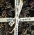 Lumin Fabrics Island Batik Woodland Warmth Batiks 5 Inch Squares, tied with a cream-colored fabric ribbon that has blue printed text.