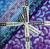 Lumin Fabrics Island Batik Secret Garden Batiks 10 Inch Squares, a set of colorful batik fabric squares with purple and blue floral and leaf patterns, tied with a black and white Island Batik ribbon.
