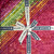 Lumin Fabrics Island Batik Posy Twist Batiks 10 Inch Squares, colorful fabric squares with floral and leaf patterns, tied with a white and blue Island Batik ribbon.