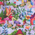 Henry Glass Fabrics Down the Fairy Path Color Principle Lilac Multi Allover Fairies fabric, featuring whimsical fairies, colorful mushrooms, vibrant flowers, and lush foliage in shades of lilac, pink, red, blue, and green.