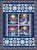 Blank Quilting Fabrics Frostykins Quilt Kit, colorful winter holiday-themed quilt with snowmen, snow-covered houses, and swirling colorful skies, surrounded by vibrant border patterns.