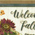 Robert Kaufman Fabrics Hello Fall Harvest Brown Welcome Fall Pumpkin Panel 24, a decorative fabric panel with fall-themed pumpkins, flowers, and welcome message in warm harvest colors.