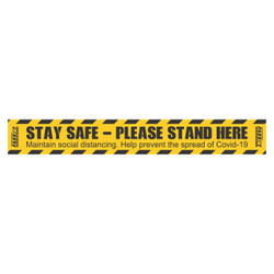 COVID-19 Social Distancing Floor Graphic, yellow and black tape with instructions to stay safe and stand here to prevent the spread of Covid-19.