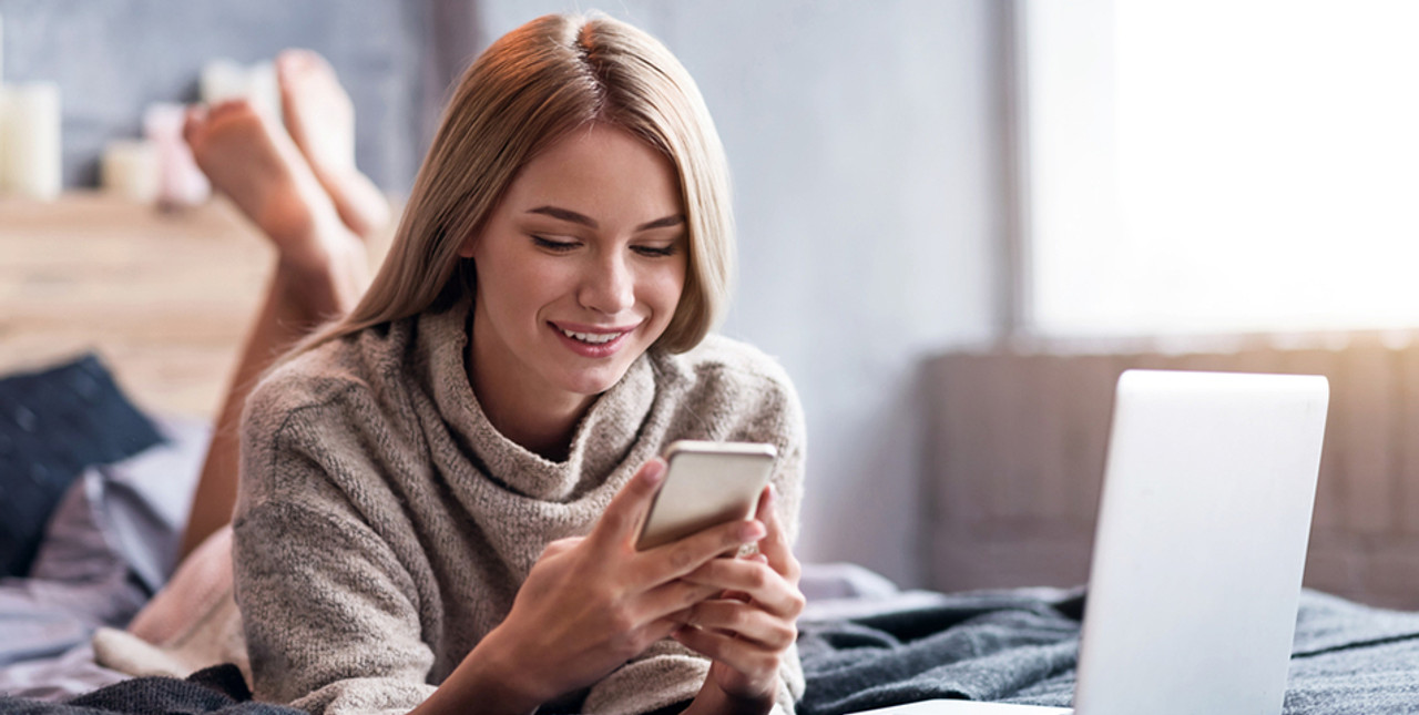 Female customer  on  phone lying on  bed  with  laptop.Free  delivery