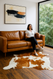 Hereford  Brown &  white  Cowhide  shown  with  lady  seated  in  one  corner  of  leather  sofa  near  a  large  window