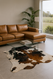 Tri  Colour  cowhide  shown  in  a  modern  setting  with  leather corner  lounge  looking  out a  window into a  paddock  with  glass  table  ,white  lamp and fern in corner