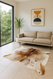 Brown &  white  brasilian  cowhide  shown  in a  modern  lounge  setting  with wall  art  and  view  out  to  garden  through  large  window