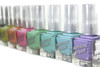 Pleasant Surprise Nail Polish, colorful nail polish bottles in various shades including pink, green, blue, and purple with silver caps arranged in a row.