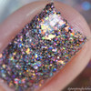 Love Is A Battlefield Nail Polish, close-up of a single nail coated in multicolored, glittery nail polish with holographic and iridescent effects.