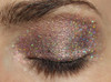 Ruler Holographic Eyeshadow, close-up image of a person's closed eye with shimmering holographic eyeshadow applying on the eyelid.