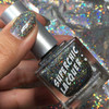 Stroke Of Midnight Holographic Nail Polish, a shimmering holographic nail polish bottle with sparkly multicolor glitter.
