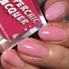 Naughty Thermal Nail Polish, pink shiny nail polish applied on manicured nails with a close-up view of the product bottle.