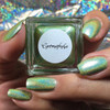 Germaphobe Nail Polish, holographic green nail polish on fingers against a colorful reflective background.