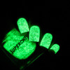 Incantation Nail Polish, glow-in-the-dark green nail polish glowing in the dark with a speckled texture.