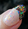 Emotional Rollercoaster Confetti Nail Polish - All Emotions Topper, close-up of a fingernail with holographic confetti glitter on a clear base, featuring vibrant colorful flakes and a black tip.