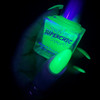 Boo Moon Green Halloween Nail Polish, glowing neon green nail polish bottle held in hand under black light.
