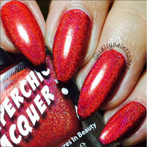 Cherub Nail Polish, close-up of fingernails painted with shimmering red-orange glitter nail polish with holographic effects.